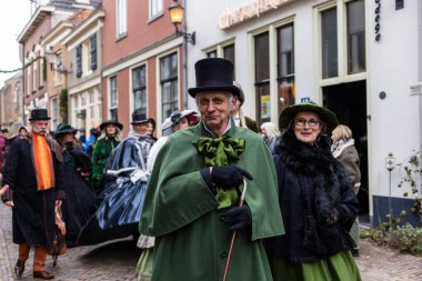 Deventer, Overijssel, Hollanda - 14.12.2025: Charles Dickens Festivali 'nde. Viktorya dönemi kostümlü çift, temalı etkinlik sırasında kaldırım taşı caddesinde yürür..