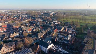 Kümelenmiş evleri, merkezi kurumsal binaları, yeşil alanları ve toplumsal yaşamı ve sürdürülebilirliği harmanlayan rüzgar türbinleri ile kenar mahalle manzarası.