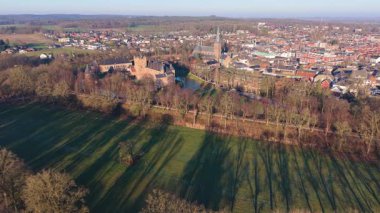 Hollanda kırsal kesiminin havadan görünüşü şato, kilise kulesi, yapraksız ağaçlar, kış tarlalarıyla çevrili yoğun evler ve kırsal-kentsel katmanlı bir bileşimin orman kenarları..