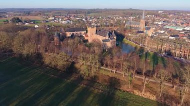 Hollanda kırsal kesiminin havadan görünüşü şato, kilise kulesi, yapraksız ağaçlar, kış tarlalarıyla çevrili yoğun evler ve kırsal-kentsel katmanlı bir bileşimin orman kenarları..