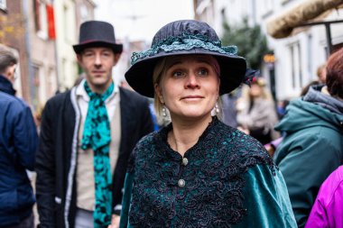 Deventer, Overijssel, Hollanda - 14.12.2025: Charles Dickens Festivali 'nde. Şenlik caddesinde, üzerinde silindir şapka olan adamın yanında duran kadife ceketli ve dantel şapkalı kadın..