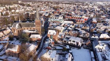 Merkezi kilise kulesi ve saat yoğunluğundaki çatılar ve dar sokaklar karla kaplıydı. Ormanlık ufuk ve modern kenar mahallelerin aksine sakin kış ışığı vardı..