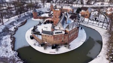 Kırmızı tuğladan kale ve donmuş ortaçağ kuleleriyle kaplı kar manzarası modern evlerle ve huzurlu kış manzarasındaki kilise kulesiyle tezat oluşturuyor..