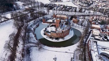 Kırmızı tuğladan kale ve donmuş ortaçağ kuleleriyle kaplı kar manzarası modern evlerle ve huzurlu kış manzarasındaki kilise kulesiyle tezat oluşturuyor..