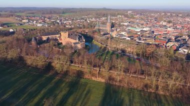 Hollanda kırsal kesiminin havadan görünüşü şato, kilise kulesi, yapraksız ağaçlar, kış tarlalarıyla çevrili yoğun evler ve kırsal-kentsel katmanlı bir bileşimin orman kenarları..
