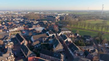 Kümelenmiş evleri, merkezi kurumsal binaları, yeşil alanları ve toplumsal yaşamı ve sürdürülebilirliği harmanlayan rüzgar türbinleri ile kenar mahalle manzarası.