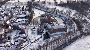 Kırmızı tuğladan kale ve donmuş ortaçağ kuleleriyle kaplı kar manzarası modern evlerle ve huzurlu kış manzarasındaki kilise kulesiyle tezat oluşturuyor..