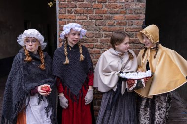 Deventer, Overijssel, Hollanda - 14.12.2025: 19. yüzyılda dört genç bir tuğla duvar ve bir sepet rulo kağıtla ayakta duruyor.