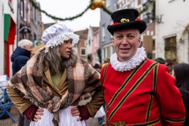 Deventer, Overijssel, Hollanda - 14.12.2025: Bayram etkinliği sırasında tarihi kostümlü iki kişi kaldırım taşı sokakta duruyor.