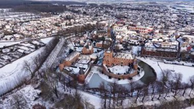 Yoğun barınaklar, kilise, ağaçlar ve açık kış tarlalarıyla çevrili, büyük kuleleri ve hendekleri olan tarihi bir kasabanın havadan görünüşü..