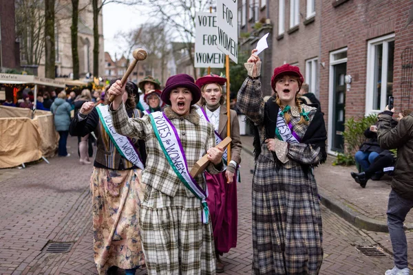 Deventer, Overijssel, Hollanda - 14.12.2025: 20. yüzyılın başlarında kadınlar için giysi yürüyüşü tarihi yeniden canlandırma sırasında kadın kuşağı ve tabelalarıyla.