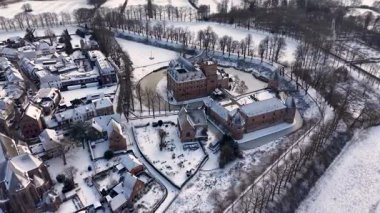 Tarihi bir kasaba, dar sokaklar, açık alanlar ve sakin, pitoresk bir manzarada yapraksız ağaçlarla çevrili, kuleleri ve hendekleri olan karla kaplı bir şatonun kış manzarası..