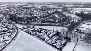 Merkezi kale ve hendekli bir kar manzarası, yakınlardaki bir kilise, yoğun konutlar, açık kış alanları ve uzak rüzgar türbinleri tarihi ve modern elementlerin bir karışımını oluşturuyor..