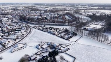 Karla kaplı bir Avrupa kasabasının engin kış manzarası. Sahne, tarihi bir kale, kilise kulesi ve aydınlık, soğuk bir sabah gökyüzünün altındaki yerleşim yerlerini yakalıyor..