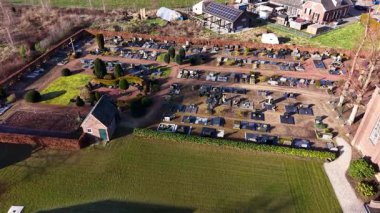 Modern cam bir naf, bitişik mezarlık ve güneş panelli evler ile güneş ışığıyla çevrili tarihi bir tuğla kilisenin yer aldığı bir Avrupa köyü manzarası..