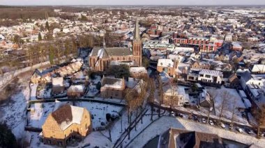 Gün batımında karla kaplı tarihi bir Avrupa kasabasının havadan görünüşü. Görkemli bir gotik kilisesi, geleneksel tuğla evleri ve Hollanda 'da kış atmosferi olan manzaralı bir şehir..