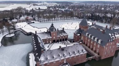 Anholt Kalesi 'nin geniş hava manzarası ve kışın çevresindeki kasaba. Geniş tuğla sarayı, donmuş resmi bahçeleri ve arka planda karla kaplanmış köy çatılarını gösteriyor..