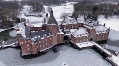 Anholt Kalesi 'nin geniş hava manzarası ve kışın çevresindeki kasaba. Geniş tuğla sarayı, donmuş resmi bahçeleri ve arka planda karla kaplanmış köy çatılarını gösteriyor..