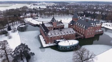 Anholt Kalesi 'nin panoramik hava manzarası ve kışın modern cam pavyonu. Büyük tuğla sarayı ve donmuş hendeği gösteriyor. Arka planda Alman kasabasının çatıları karla kaplı..