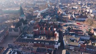 Gotik bir katedrali, kırmızı tuğlalı çatıları ve yumuşak sabah güneşi altında merkezi bir şehir meydanı olan tarihi bir Avrupa şehir merkezinin yüksek açılı görüntüsü..