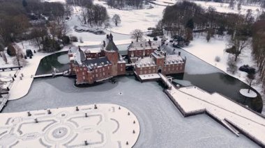 Almanya 'daki Ortaçağ Burg Anholt kalesinin hava görüntüsü. Tuğla kale, donmuş bir hendek ve kışın gökyüzünün altında karla kaplı bahçelerle çevrilidir. Kışın çarpıcı tarihi mimari.