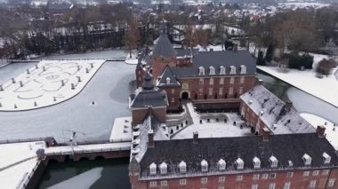 Almanya 'daki çarpıcı Burg Anholt kalesinin hava görüntüsü. Ortaçağ tuğla mimarisi, karlı bir avlu ve donmuş bahçe havuzları. Kuzey Ren-Vestfalya 'da resim gibi bir kış manzarası.