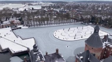 Almanya 'daki Burg Anholt kalesinde karla kaplı Barok bahçeleri ve donmuş göletlerin havadan görünüşü. Tarihsel ortaçağ mimarisi ve şehir manzarası kış manzarasında. Resimli seyahat hedefi.