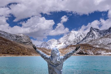 The man hands up and happy alone after arrived at the milk lake in Yading. clipart
