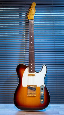 Odadaki woden masanın üzerinde güneş patlaması elektro gitar telecaster şekli (altın donanım). İşsizlik ve müzik konsepti. Duvar kağıdı veya arkaplan.