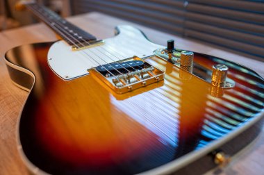 Odadaki woden masanın üzerinde güneş patlaması elektro gitar telecaster şekli (altın donanım). İşsizlik ve müzik konsepti. Duvar kağıdı veya arkaplan.