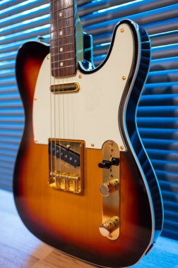 Odadaki woden masanın üzerinde güneş patlaması elektro gitar telecaster şekli (altın donanım). İşsizlik ve müzik konsepti. Duvar kağıdı veya arkaplan.