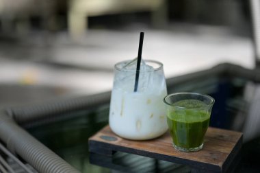 Buzlu yeşil çay fincanı ve cam süt kavanozları kafenin arka planındaki ahşap masada fotokopi alanı ile birlikte..