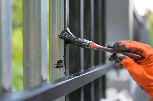 Boya fırçası ve turuncu eldivenle çeliği boyayan işçiler seçici bir şekilde ellerinde.