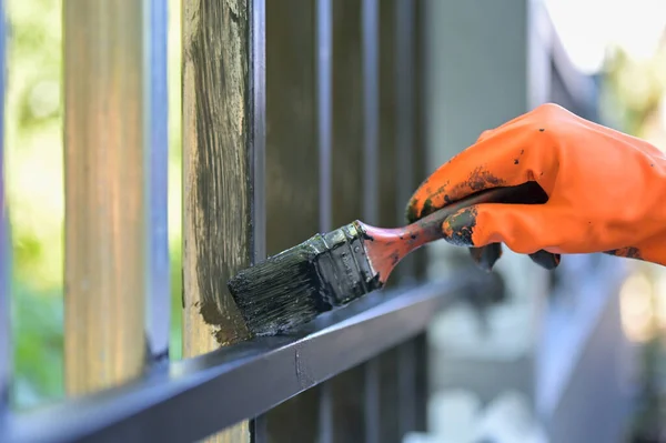 Boya fırçası ve turuncu eldivenle çeliği boyayan işçiler seçici bir şekilde ellerinde.