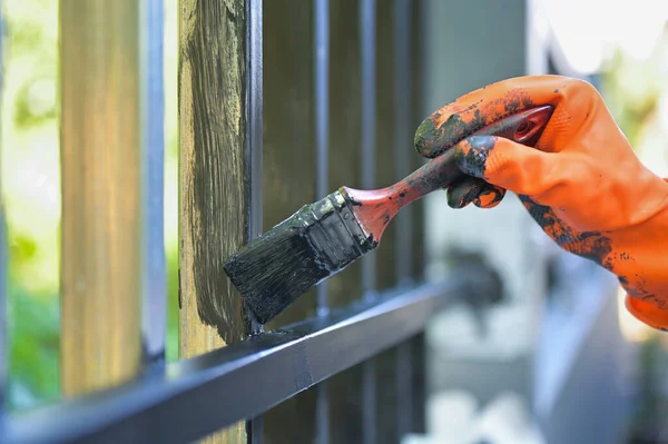 Boya fırçası ve turuncu eldivenle çeliği boyayan işçiler seçici bir şekilde ellerinde.