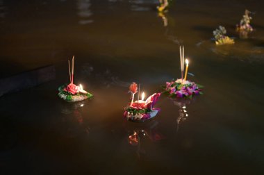 Loy Krathong festivali. İnsanlar Tayland 'daki Loy Krathong festivalini kutlamak için çiçek ve mum alıp suyun üzerinde yüzüyor..