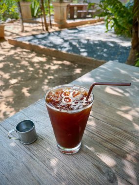 Cold Brew - Kafe Seçici odak noktasındaki eski ahşap masa altlığı üzerinde bir bardak buzlu americano kahvesi. 