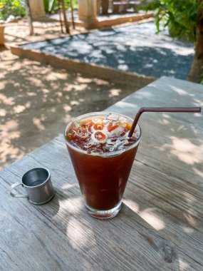 Cold Brew - Kafe Seçici odak noktasındaki eski ahşap masa altlığı üzerinde bir bardak buzlu americano kahvesi. 