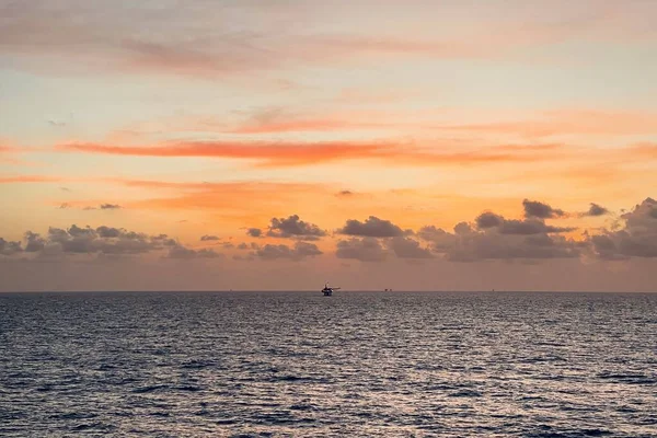 Beautiful sunset in the Sea with offshore well head platform and supply boat in dramatic tone.