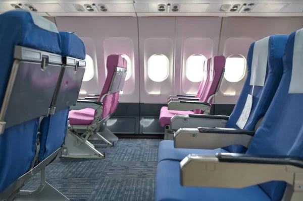 Empty passenger airplane seats in the cabin blue and pink with social distancing to prevent covid19 infection during pandemic.