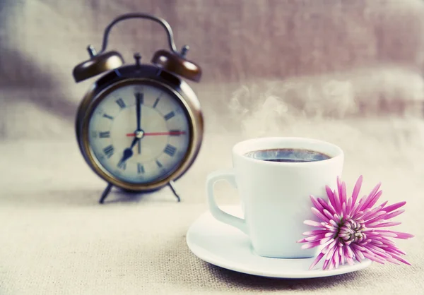 Una taza de café con flor y un despertador en el fondo, procesamiento cruzado — Foto de Stock