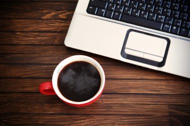 Laptop ve kahve fincanı ahşap masada. Yukarıdan görüntüle