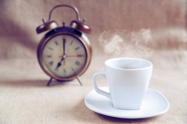 Bir fincan kahve ve bir çalar saat arka planda, çapraz işleme 