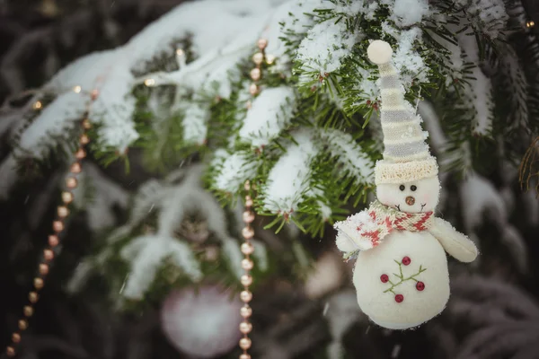 Снеговик в зимнем костюме рядом с рождественской елкой — стоковое фото