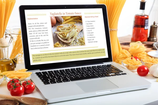 Ноутбук с рецептом на столе с макаронами и овощами — стоковое фото