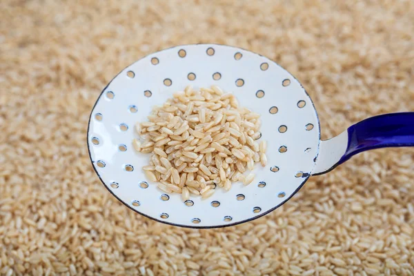 Cuchara vieja metálica sobre fondo de arroz sin refinar — Foto de Stock