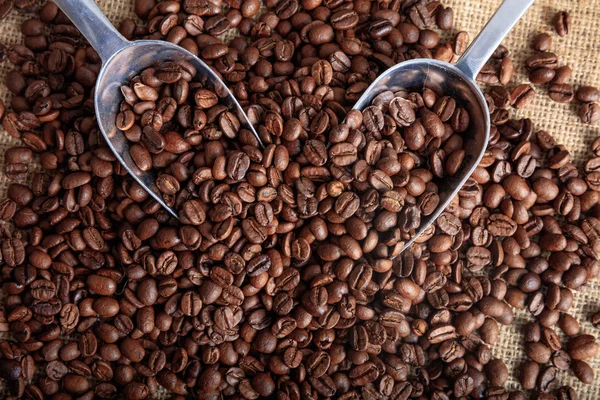 Coffee beans and two scoops on a burlap — Stock Photo, Image