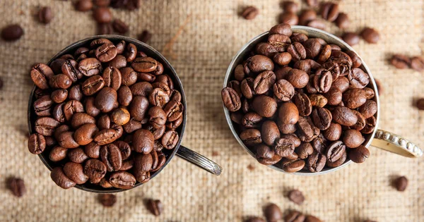 Coffee beans in old cups on a burlap — Stock Photo, Image