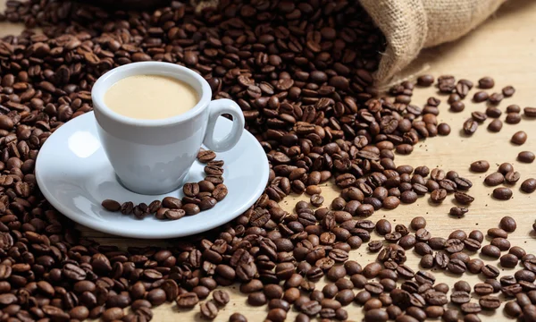 Granos de café de un saco y una taza de café —  Fotos de Stock