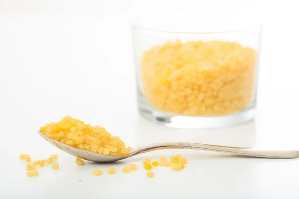 Желтый сахар в ложке и стакане — стоковое фото